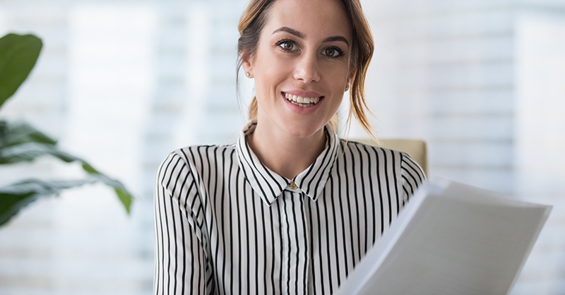 woman smiling while holding paperwork