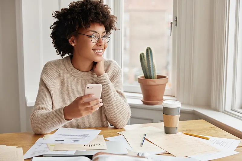 Woman smiling and looking relieved while dialing on her phone