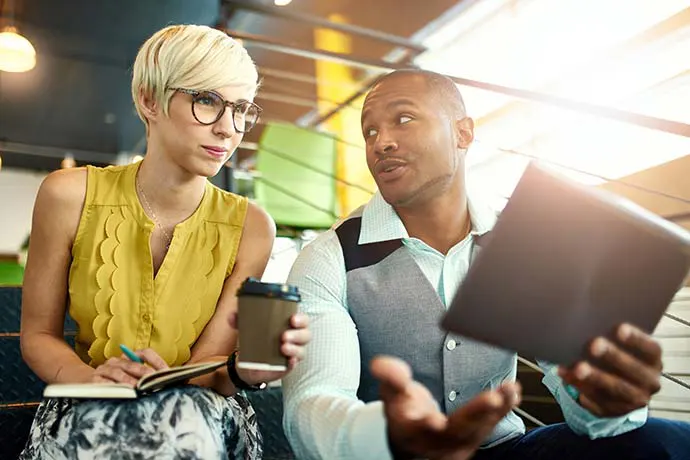 Professional man and woman looking at a tablet