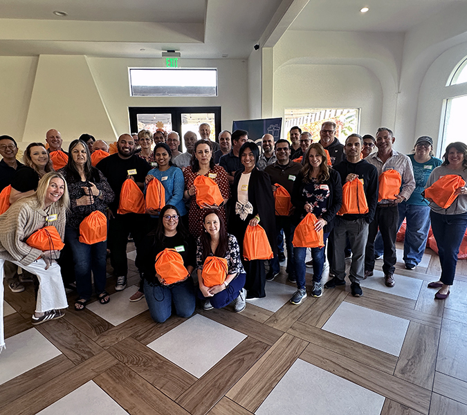 Group of TaxAudit Employees holding bags of school supplies