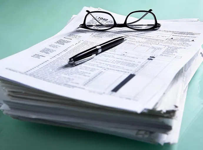 Stack of tax forms with glasses sitting on top