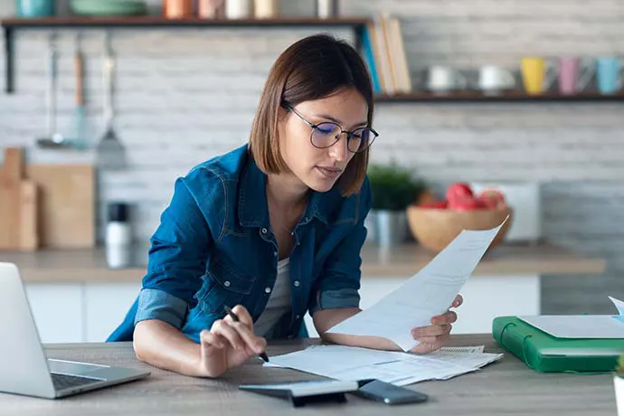 woman looking at paperwork and using a calculator