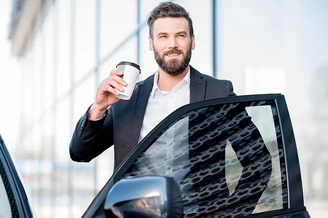 Man by car holding a coffee